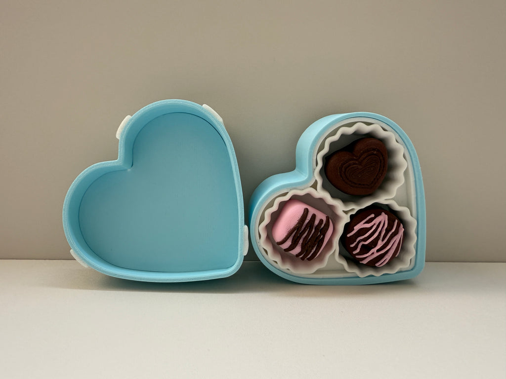 Heart-shaped blue box with pink and brown chocolates on a neutral background
