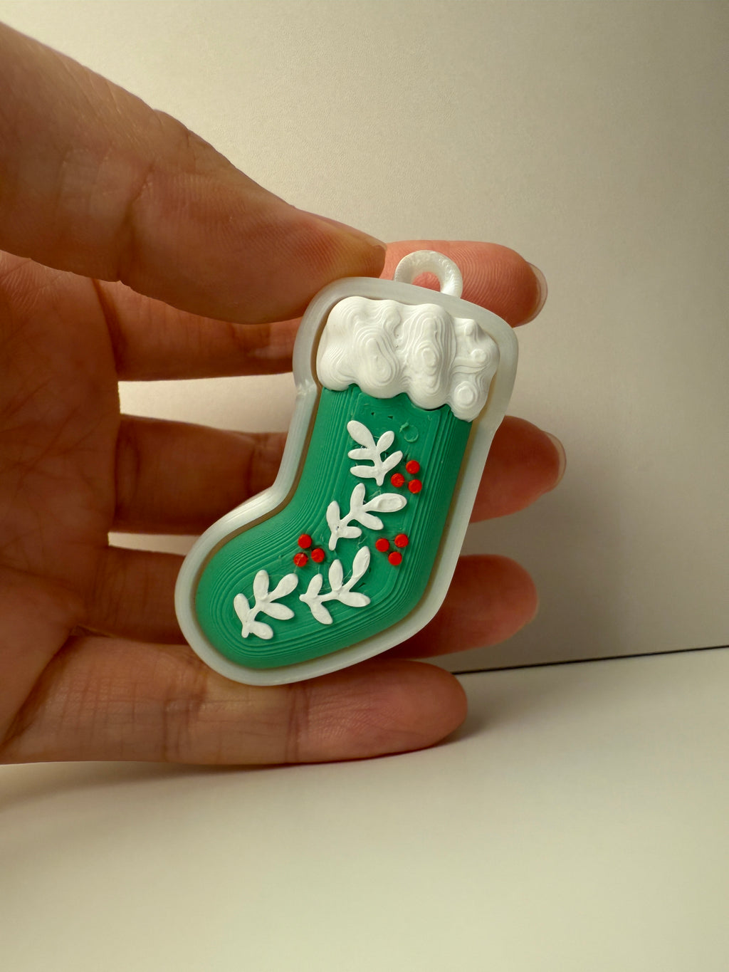 Hand holding a green and white Christmas stocking ornament.