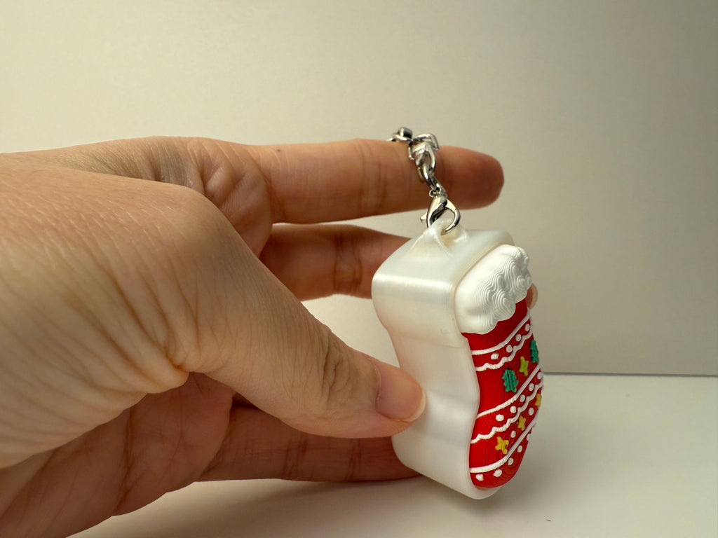 Hand holding a white and red keychain with a chain